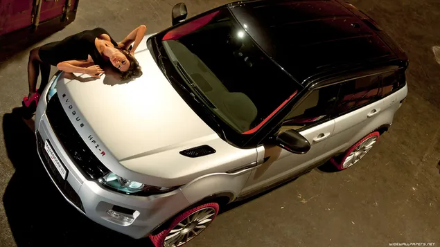 En sort/hvit range rover med rødstripet topp og en kvinne i svart kjole ved siden av 4K bakgrunn