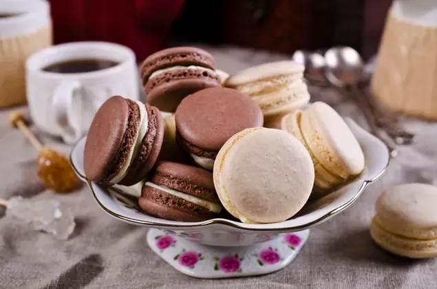 Semangkuk penuh Chocolate dan Vanilla Macarons dengan teh dengan madu