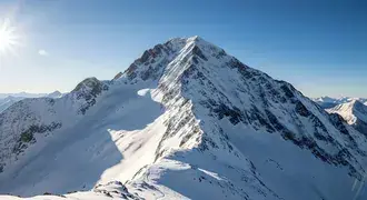 a breathtaking sunlit mountain peak rises above a landscape of untouched snow and clear blue skies, capturing the pure majesty and tranquility of wint download