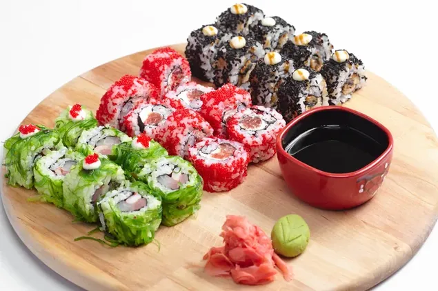 O grămadă de rulada de sushi savuroasă cu sos de soia, ghimbir roz murat și wasabi într-o placă de lemn circulară 4K imagine de fundal