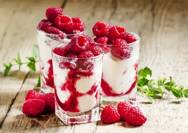 Un got de melmelada cremosa de gerds amb fruites de gerds al damunt col·locat en una taula de fusta 4K fons de pantalla