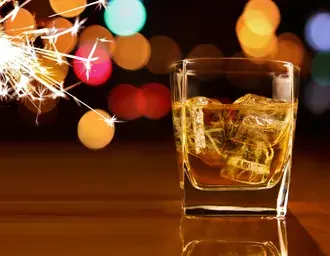 Tapeta Sklenka whisky s ledem a prskavky na straně s bokeh světelnými efekty 4K