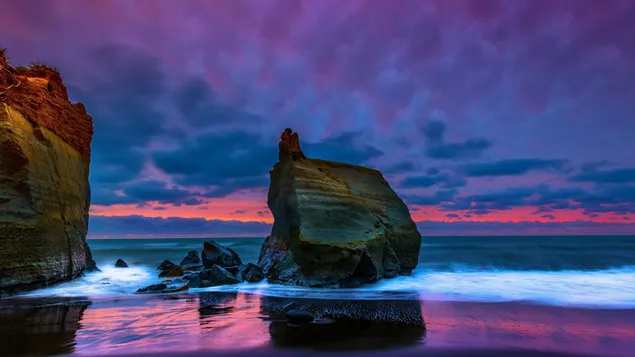 Ein riesiger Stein im Meer bei Sonnenuntergang 4K Hintergrundbild