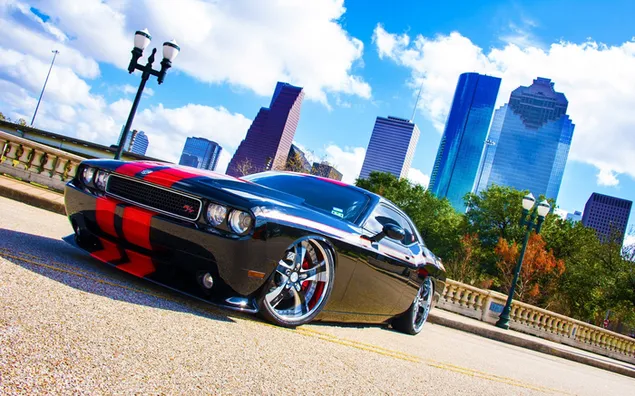 elegantni cerny dodge challenger s cervenymi pruhy na pozadi panoramatu houstonu. stahnout