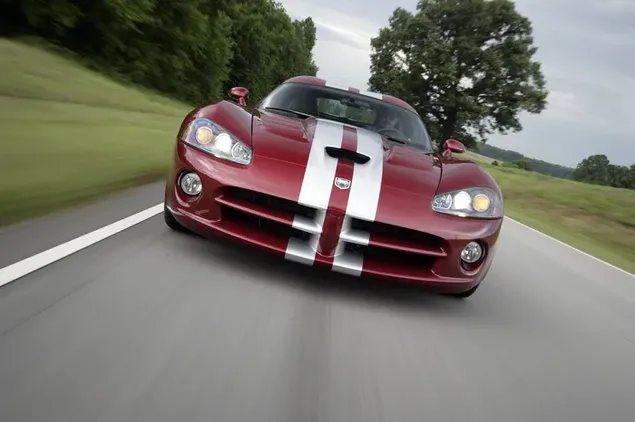 A state-of-the-art red and white sports car Dodge Viper SRT 10 on an asphalt road in the middle of trees and grass