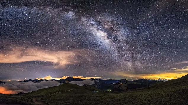Un pueblo entre montañas y niebla, con cúmulos de estrellas y nubes claramente visibles por la noche 4K fondo de pantalla