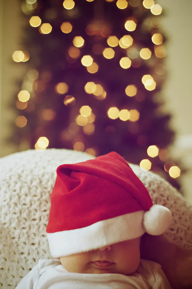 Em bé đáng yêu với chiếc mũ của ông già Noel và nền đèn bokeh Giáng sinh
