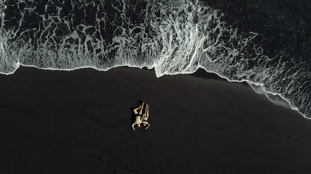 Aerial shot of a black beach with a lovely couple  4K wallpaper