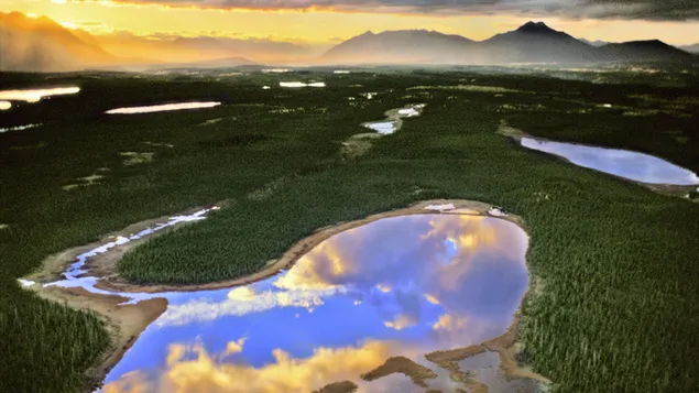 Alaska met zijn mistige bergen, groene natuur en helder water dat wordt weerspiegeld door de wolken 2K achtergrond
