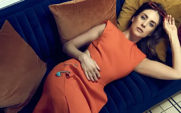 Hình nền Alison Brie, nữ diễn viên tóc nâu mặc một chiếc váy màu cam nằm trên chiếc ghế sofa màu xanh với những chiếc gối màu nâu 4K