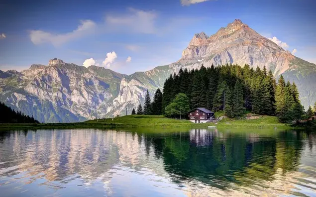 Alpes en la asombrosa naturaleza de Suiza con colinas, árboles y una pequeña casa junto al lago 4K fondo de pantalla