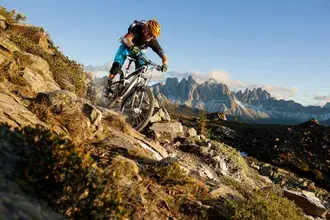 Tapeta Sportovec s batohem v helmě jezdí na horském kole po drsných polních cestách na vrcholu 4K