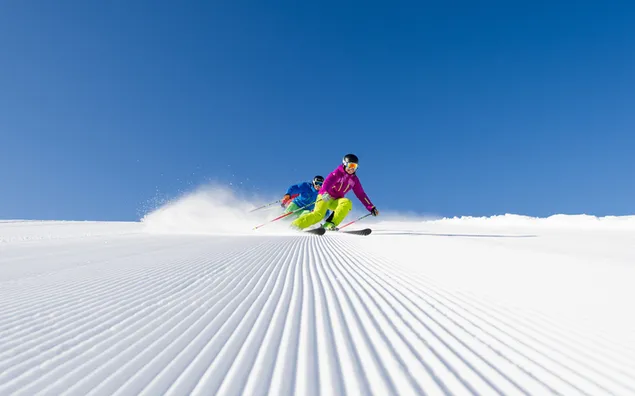 Esportistes esquiant a la neu sota un cel blau baixada