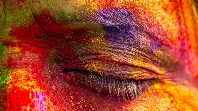 Auge einer Person, die sich beim Holi-Festival mit bunten Farben amüsiert