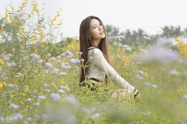 Hermosa chica asiática rodeada de pequeñas flores bonitas