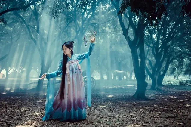 Schéin asiatesch Fra danzt am Bësch an hiren traditionelle Kleeder 4K Tapeten