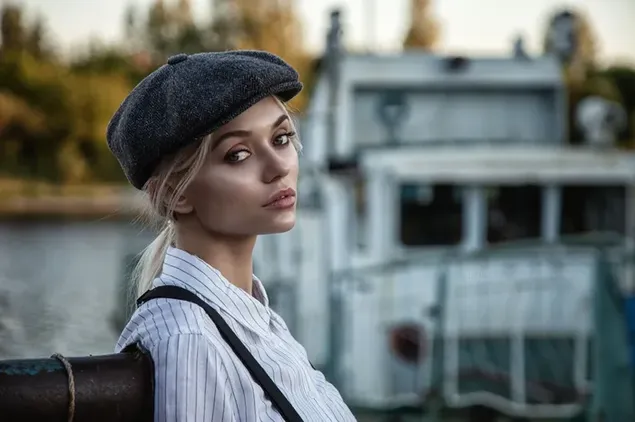 Beautiful blonde model in black hat and white shirt in front of tree, sky and architecture blur background 2K wallpaper