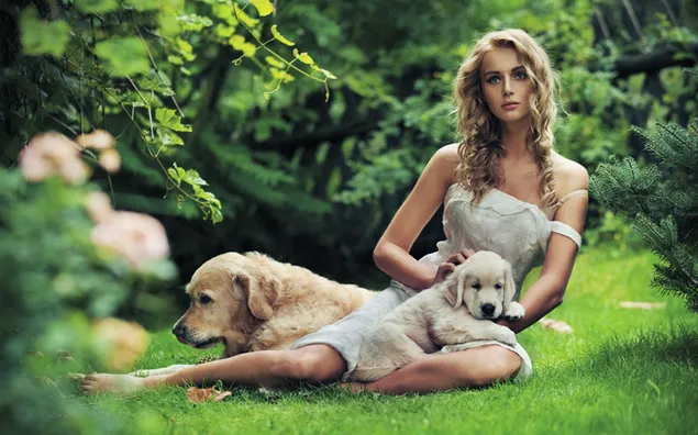 Beautiful blonde woman in white dress and cute yellow and white dog among flowers, grass and trees
