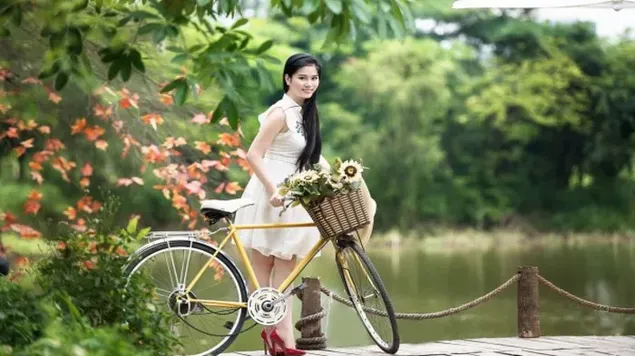 hermosa chica de pie en bicicleta entre arboles por camino de madera en el lago descargar
