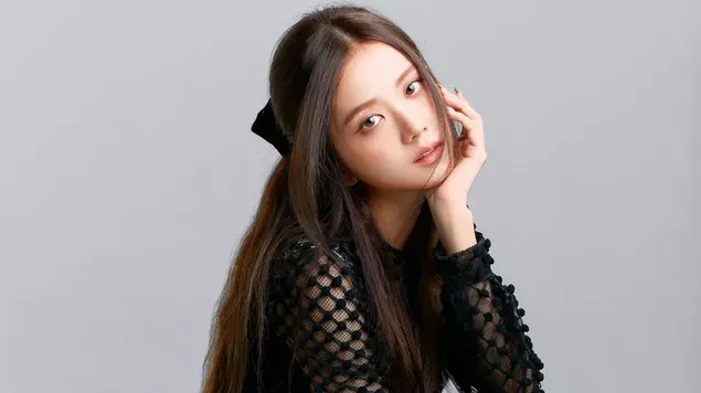 Beautiful lead singer of girl group Blackpink poses in black dress on white background with hand on chin