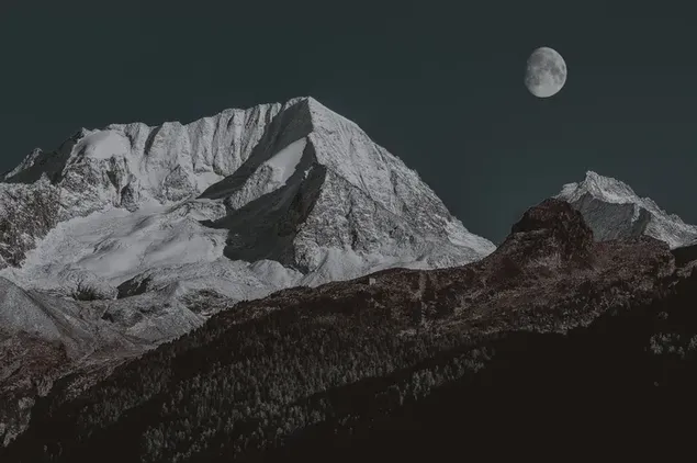 Schöne Aussicht auf die schneebedeckten Berge, die in der Abenddämmerung vom Vollmond beleuchtet werden 2K Hintergrundbild