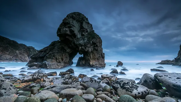 Bemooste Steine ​​und geformte Felsen über dem Meer unter bedecktem Himmel