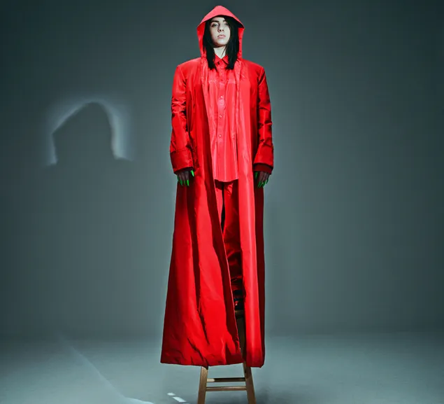 Billie Eilish wearing all red outfit standing in stool