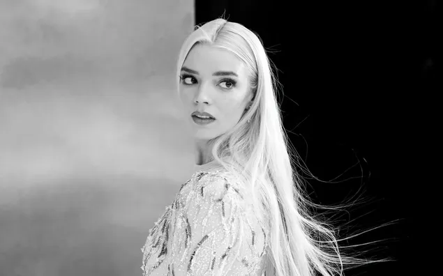 Black and white captivating photo of beautiful young actress Anna Taylor Joy with long blonde hair and a white outfit