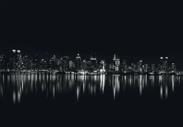 Schwarz-Weiß-Bild von Stadtgebäuden, die sich in der Abenddämmerung auf dem Meer spiegeln herunterladen