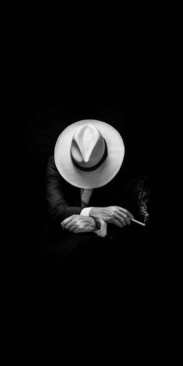 Schwarz-Weiß-Foto eines Mannes in Anzug und weißem Hut, der eine Zigarette hält herunterladen