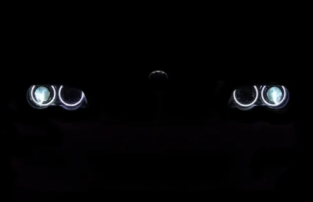 czarne bmw z wlaczonymi reflektorami, szlachetna postawa na czarnym tle pobierz