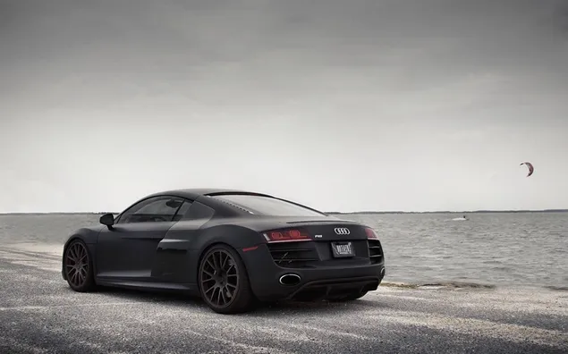 Black color steel rim design marvel audi r8 with parachute and sea view in the sky on a cloudy day