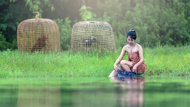 Swartharige vrou in 'n rooi minirok wat klere in die meer by die woud was 4K muurpapier