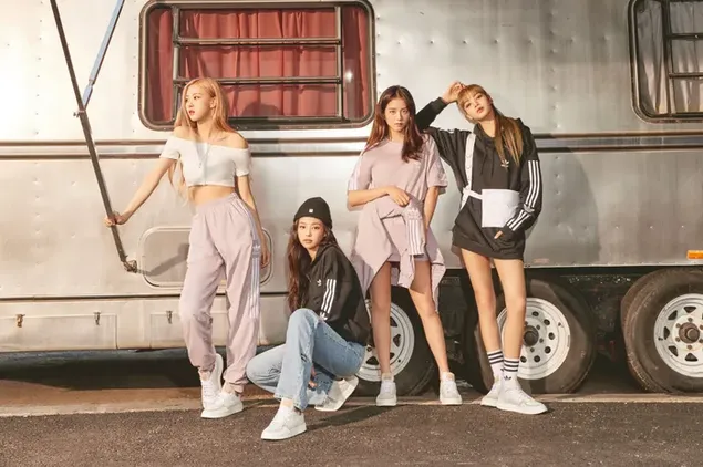Leden van de Blackpink-meidengroep Jennie, Rose, Lisa en Jisoo staan ​​voor een grijze caravan