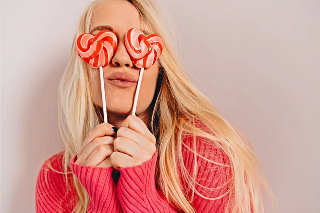 Taustpilt Blond tüdruk roosas kampsunis, käes kaks südamekujulist pulgakommi 4K