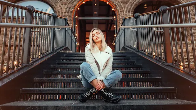 vajza modele bjonde e ulur ne shkallet e nje ndertese shkarkim