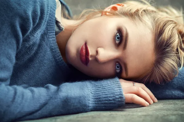 Blauäugiges Mädchen in einem blauen Pullover 2K Hintergrundbild