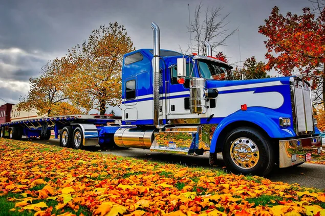 Camión azul estacionado bajo hojas de otoño descargar