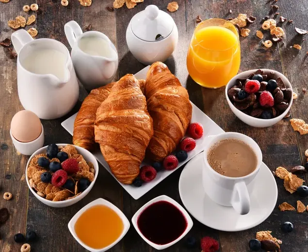 Pan, frutas, cereal, leche, café y jugo para desayunar en mesa de madera 4K fondo de pantalla