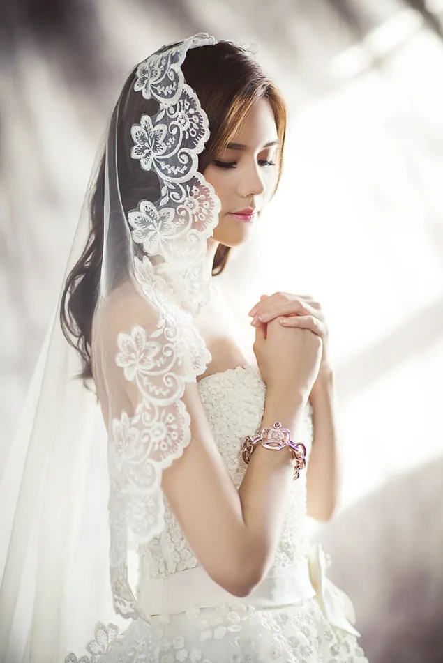 Braune langhaarige Frau in einem wunderschön gestalteten Hochzeitskleid vor verschwommenem Hintergrund HD Hintergrundbild