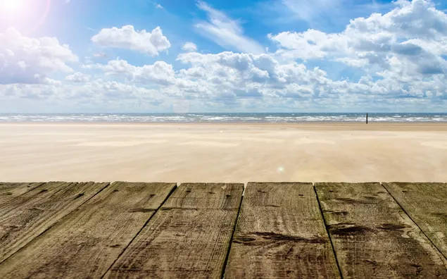 Muelle de madera marrón bajo un cielo nublado y soleado, banco de madera, playa