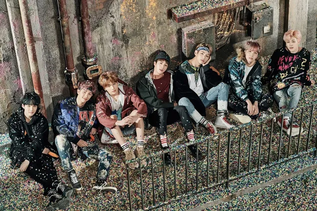 BTS-Jungs sitzen zusammen an der Seite des Gebäudes herunterladen