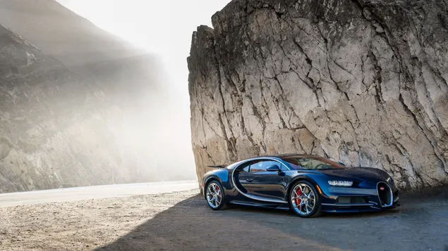 Bugatti з красивим дизайном ободів чорного кольору на краю освітленої сонцем асфальтової дороги та скель завантажити