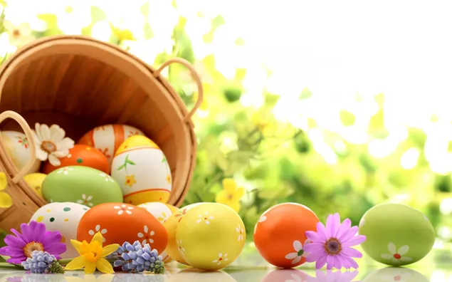 Bunte und gemusterte Eier in den bunten Blumen des Korbes