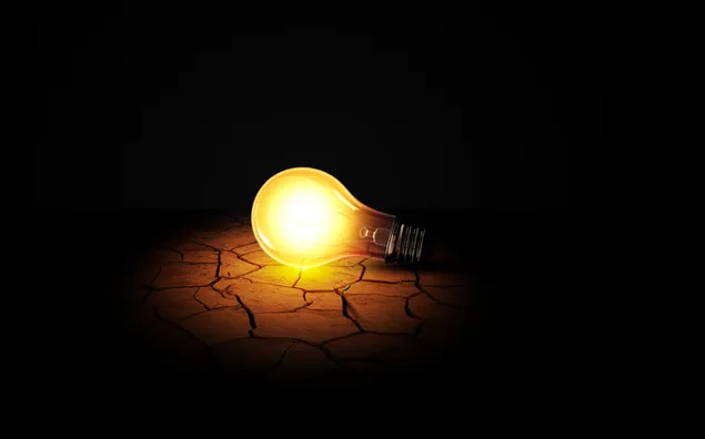 Burning light bulb with yellow light on earth ground turning into a thirsty desert download