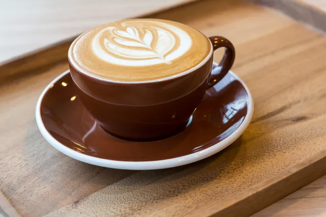 Café sobre mesa de madera, crema con forma de hoja