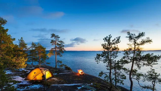 海沿いの木々の下に設置されたキャンプテントと夕方の火事 2K 壁紙
