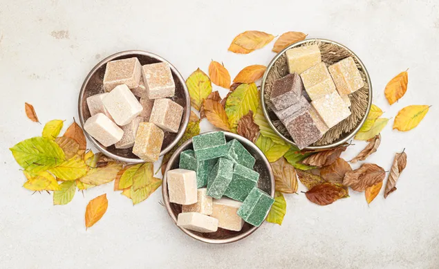 يتم تقديم الحلوى على أطباق بين أوراق الصيف والخريف على خلفية بيضاء 4K خلفية