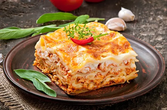 Cheesy beef lasagna top with herbs and chili pepper