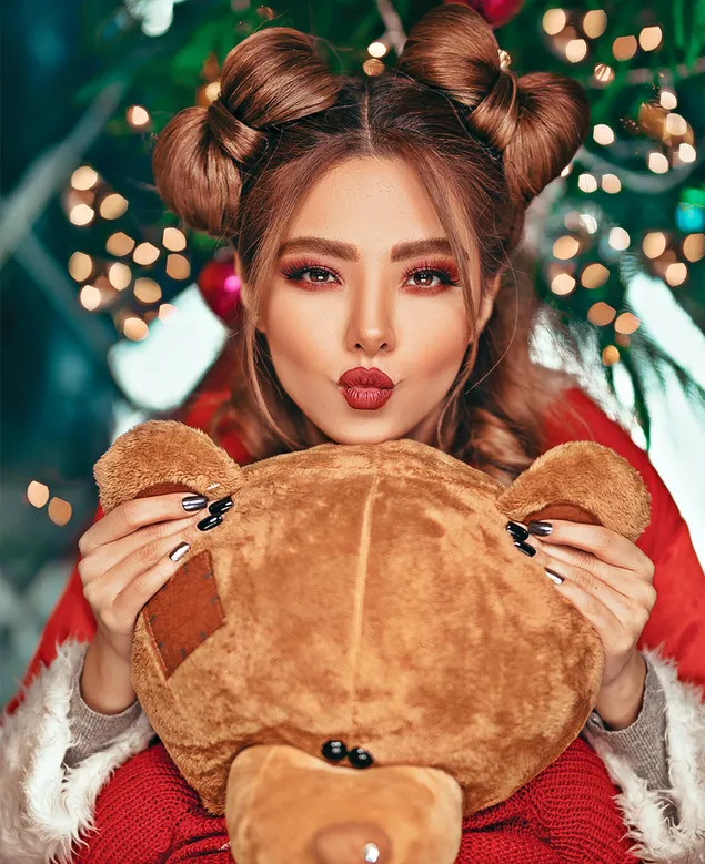 Chica morena con traje de Papá Noel abrazando a un oso de peluche